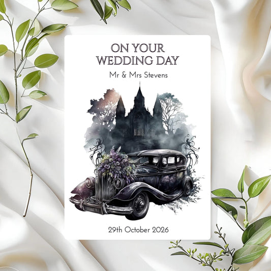 Wedding card with vintage car and castle illustration on a white fabric background with green leaves.