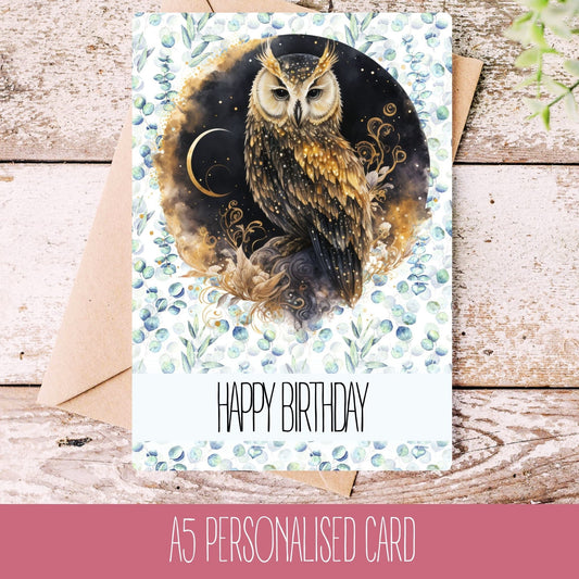 A personalised handmade birthday card with an owl design, placed on a wooden surface with a white envelope behind it.
