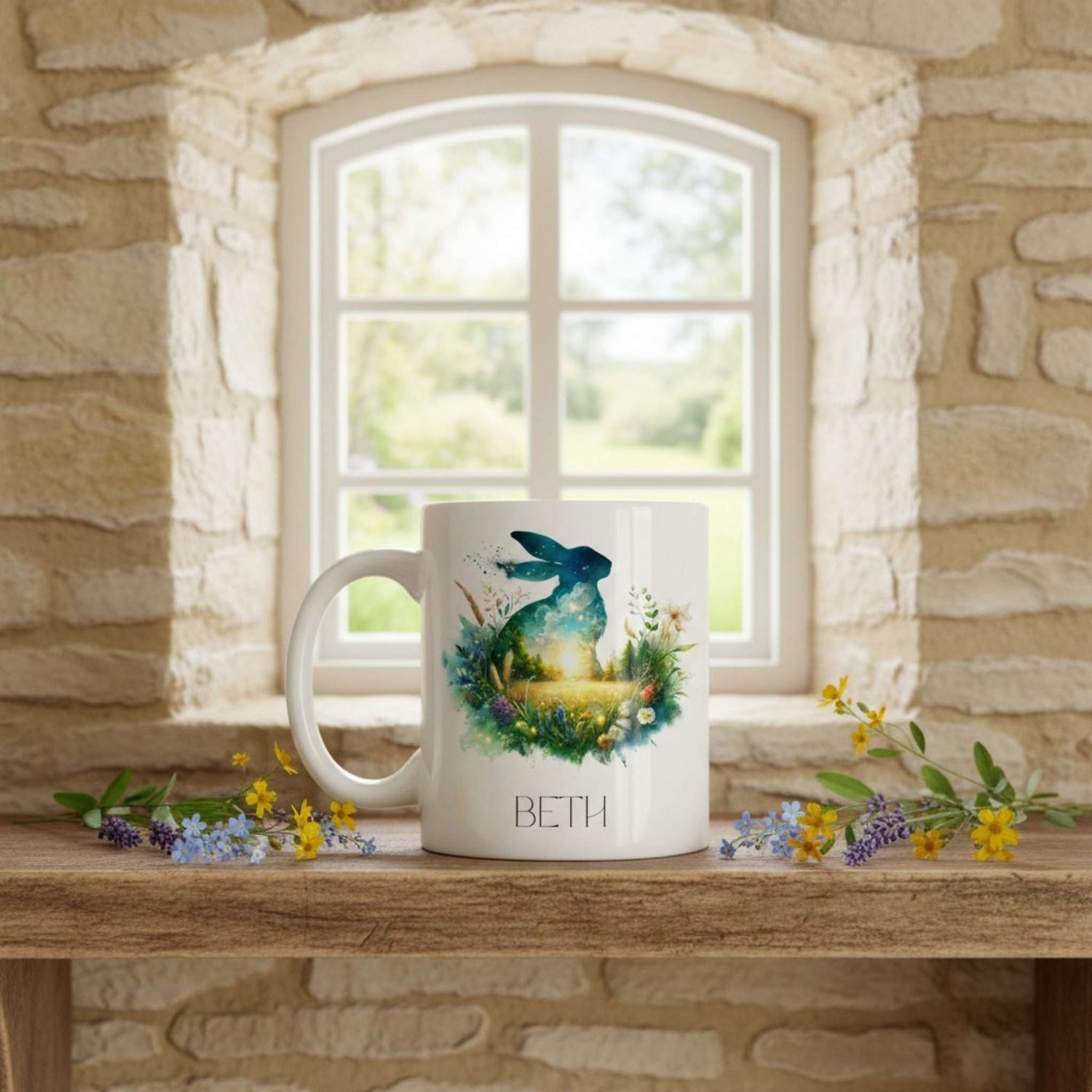 Mug with a hare design and 'BETH' on a wooden surface with a window in the background.