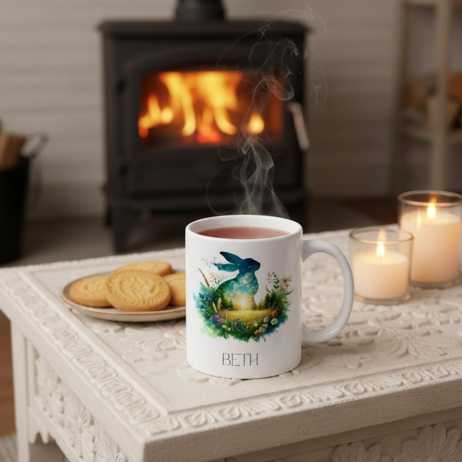 White mug with a design of a hare and text 'BETH' on a table in front of a fireplace.