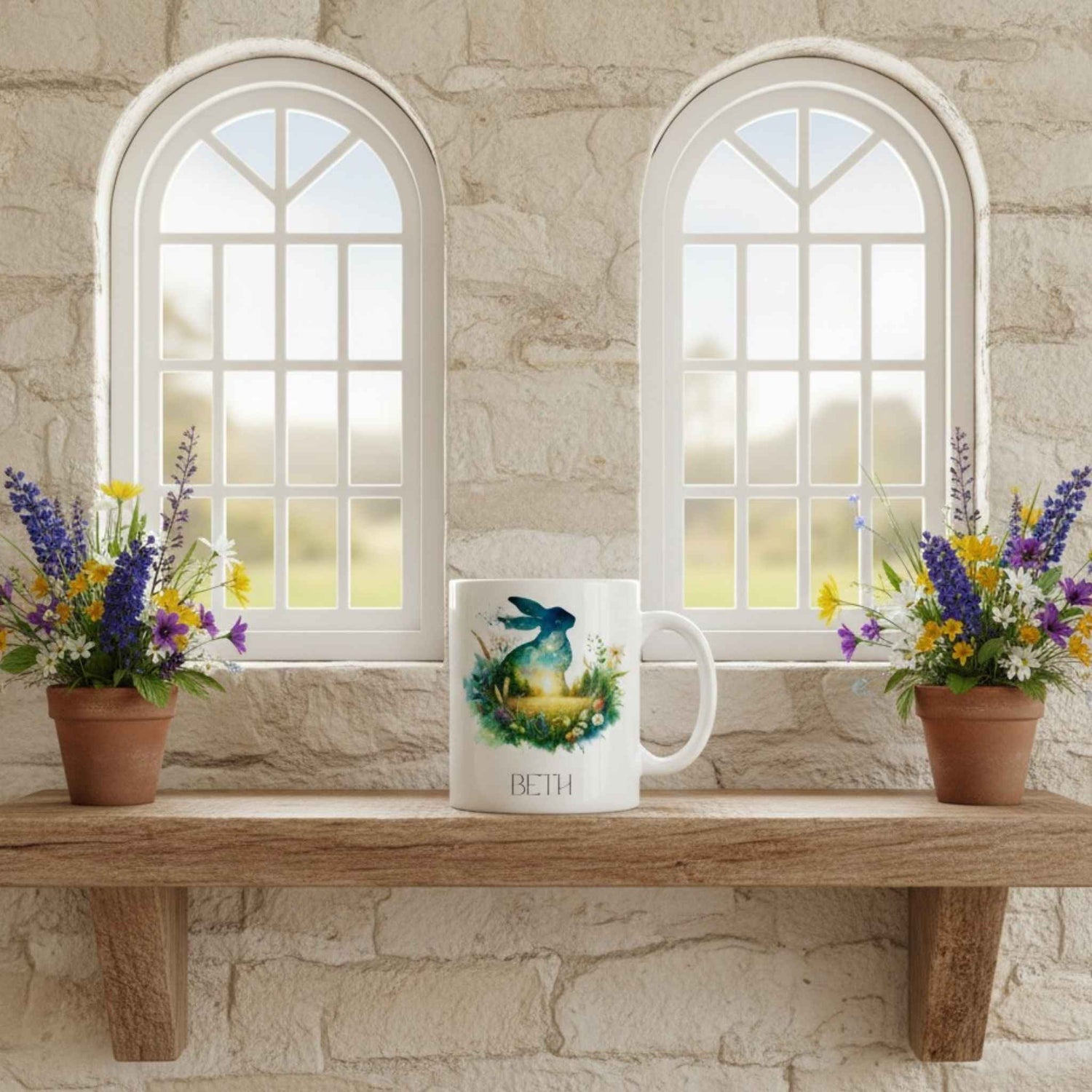 Mug with a hare design on a wooden shelf with flowers in front of stone walls and windows.