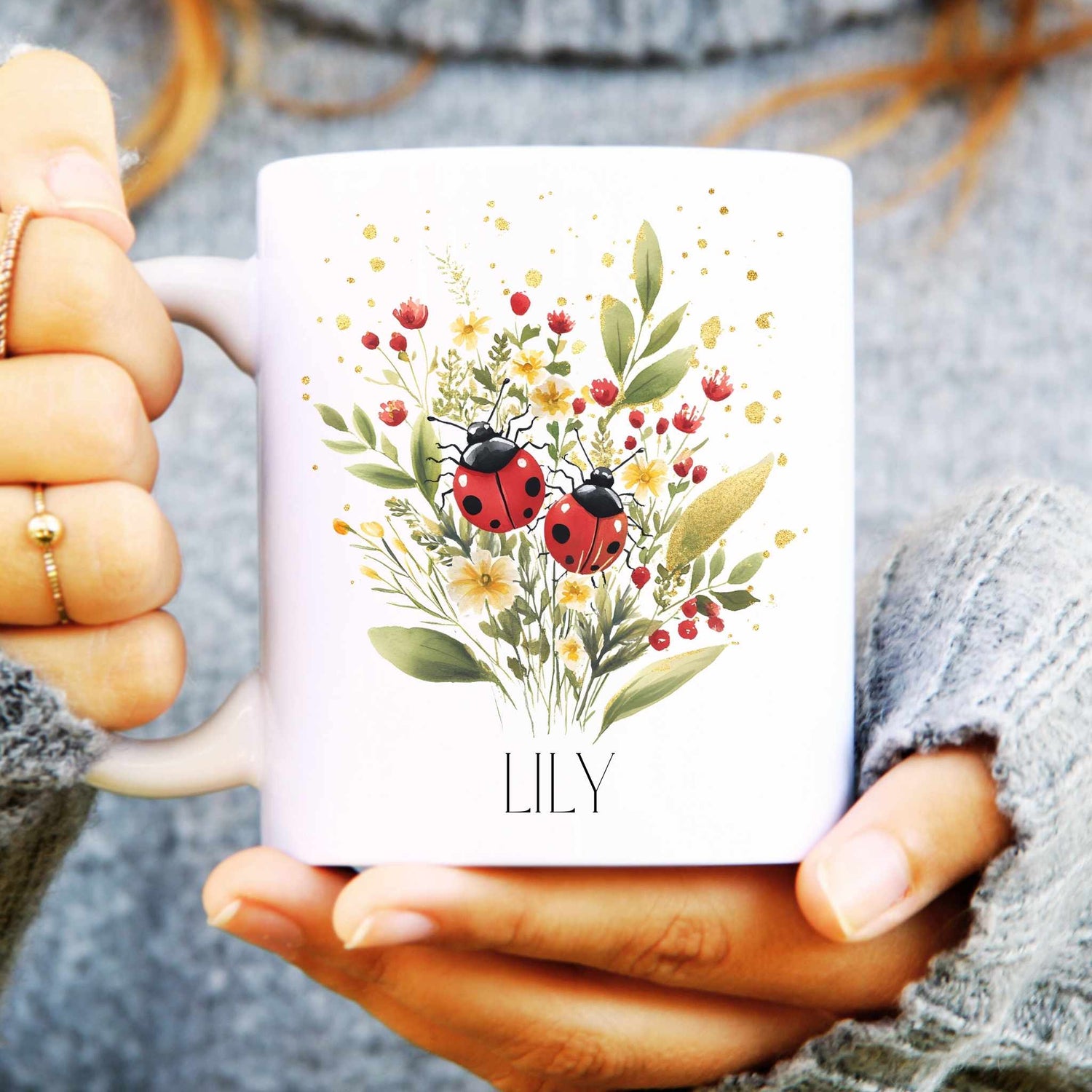 White mug with floral and ladybug design held by a person