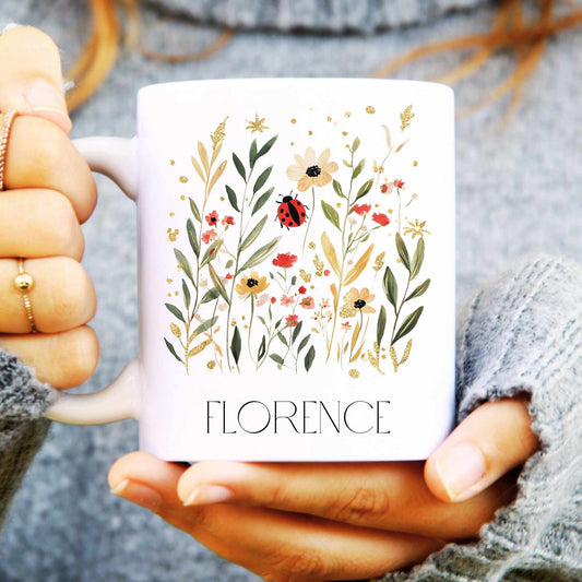 Person holding a mug with floral ladybird design and 'FLORENCE' text