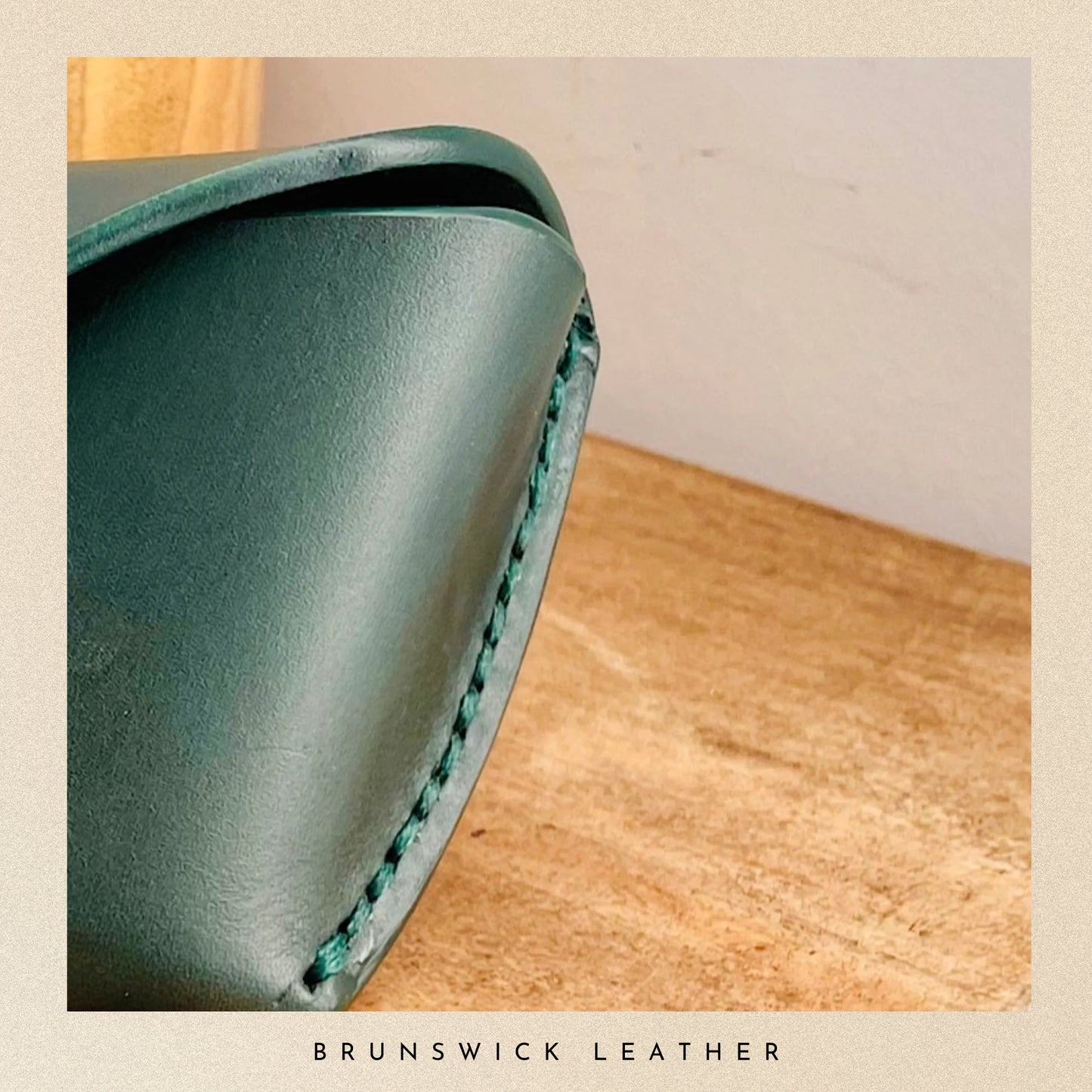 Green leather wallet on a wooden surface with 'Brunswick Leather' branding.
