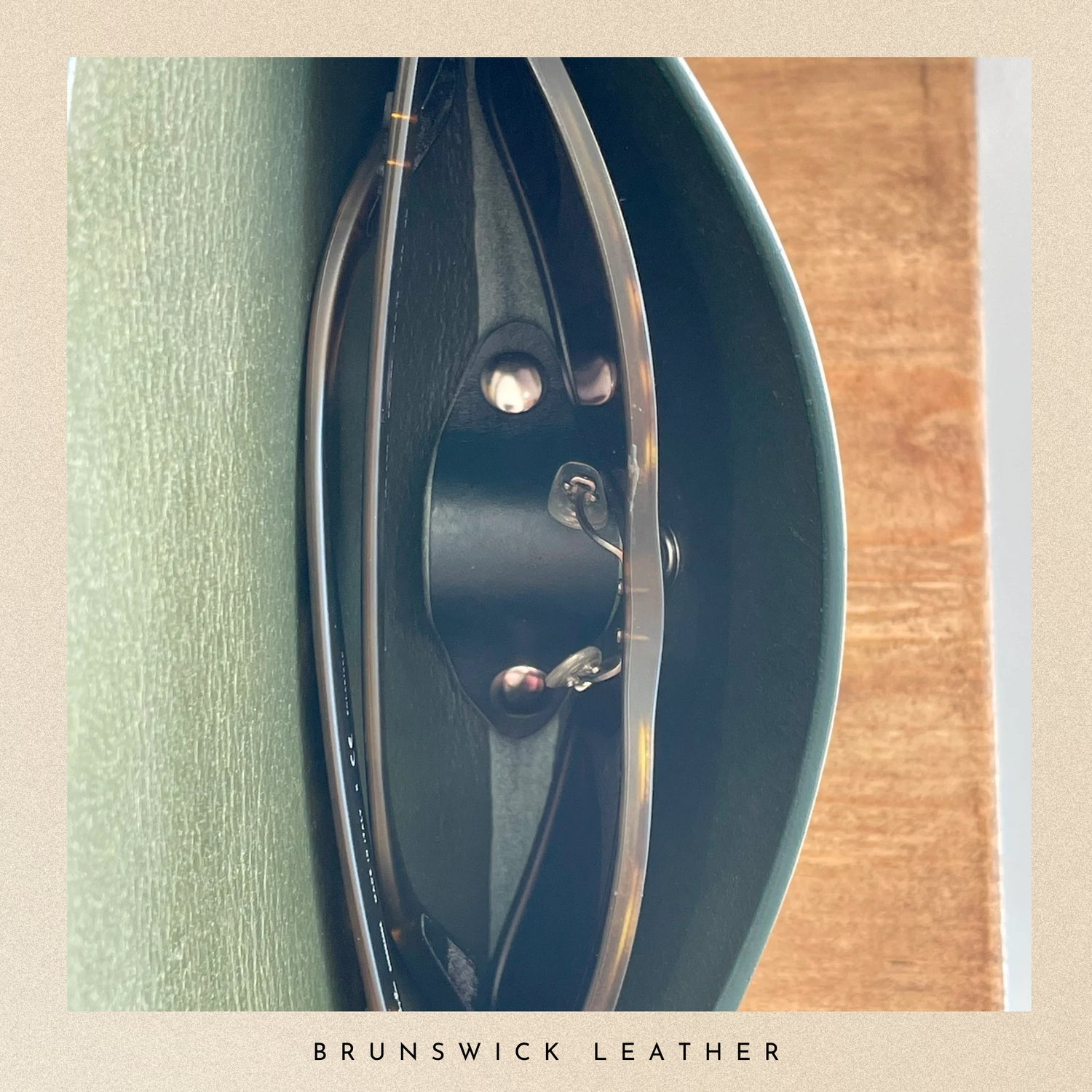 Close-up of a leather product with 'Brunswick Leather' branding on a wooden surface.