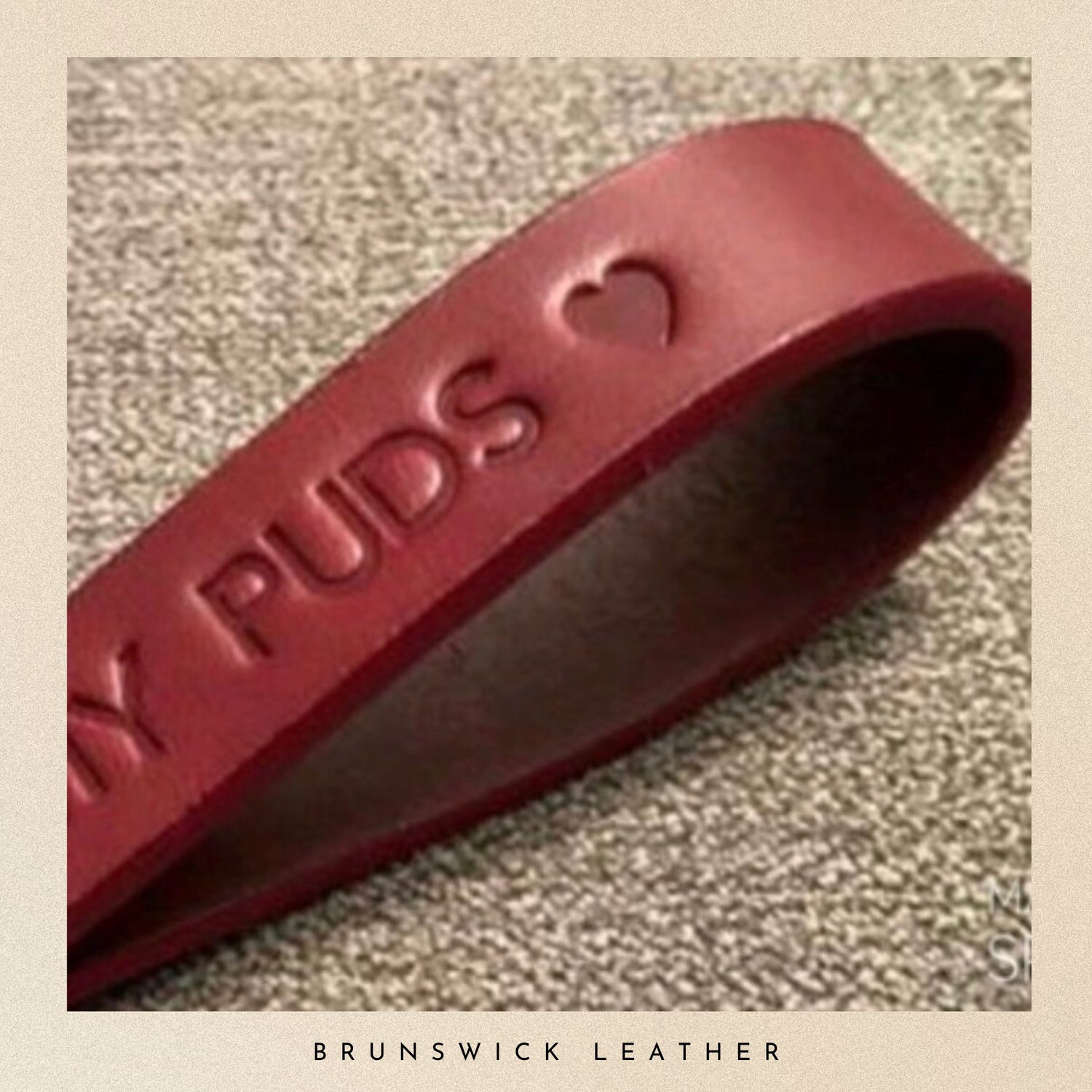 Burgundy leather strap with 'Puds' branding on a textured surface, featuring the brand 'Brunswick Leather'.