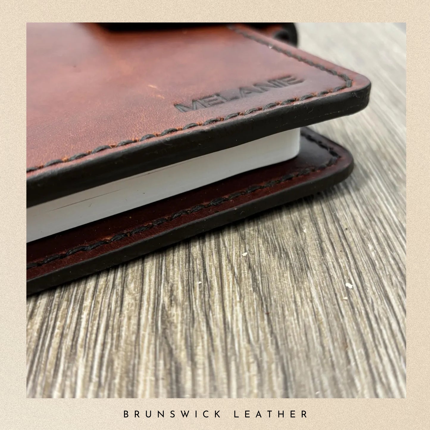 Close-up of a leather-bound notebook with 'Melange' branding on a wooden surface, featuring the brand 'Brunswick Leather'.