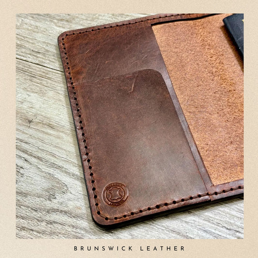 Brown leather wallet on a wooden surface with 'Brunswick Leather' branding.