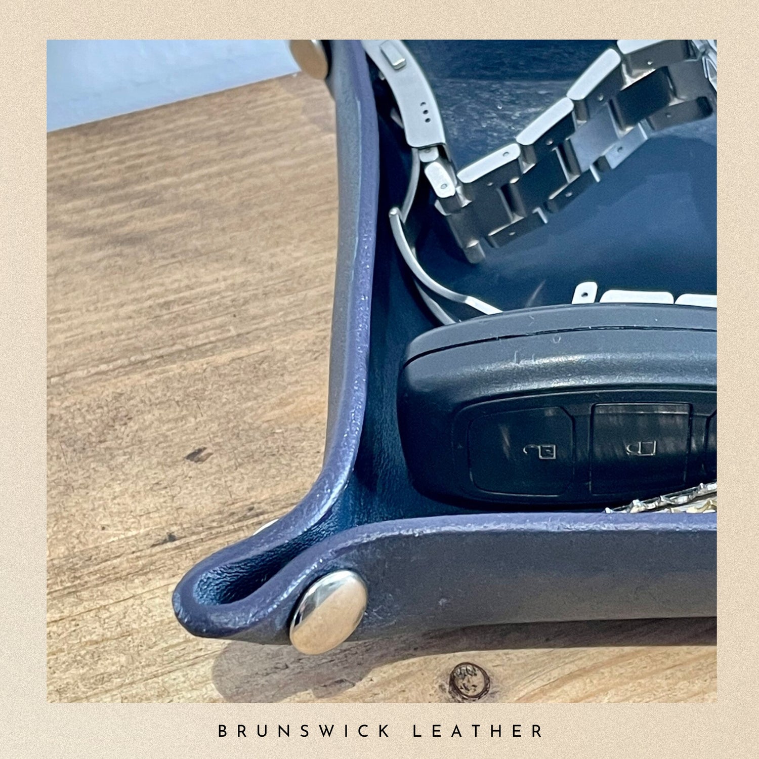 Close-up of a blue leather chair with metallic accents on a wooden surface, featuring the 'Brunswick Leather' brand.
