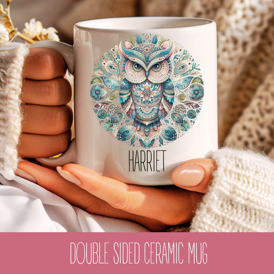 A personalised ceramic coffee cup with a mandala design and the name 'Harriet' printed on it, held in a person's hand.