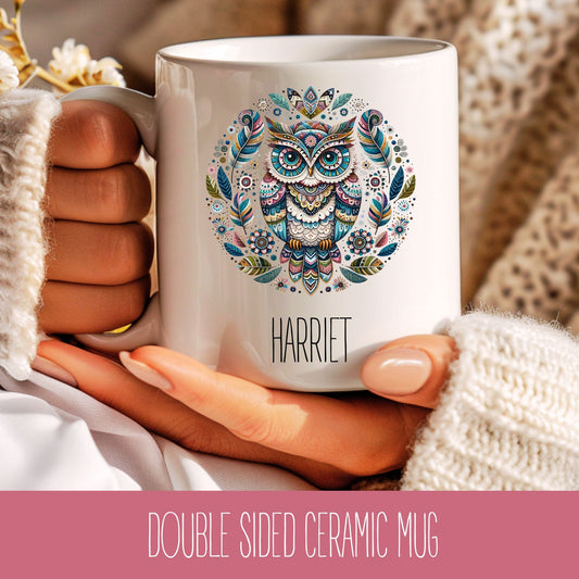 A personalised ceramic coffee mug with a colourful mandala owl design and the name 'Harriet' printed on the side, held in a person's hand.