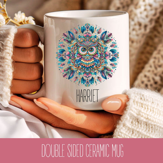 A personalised ceramic mug with a colourful mandala design and an owl in the centre, held in a person's hand. The mug has a name 'Harriet' printed on it.