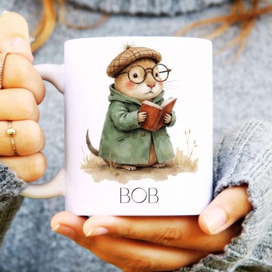 Mug with a mole illustration in a coat and hat holding a book, labelled 'BOB', held by a person.