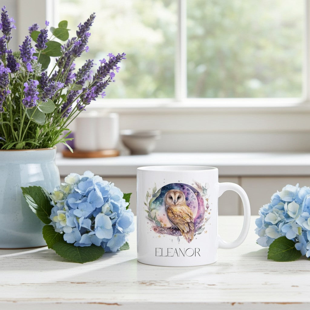 White mug with owl design and 'Eleanor' text on a table with flowers and a plant.