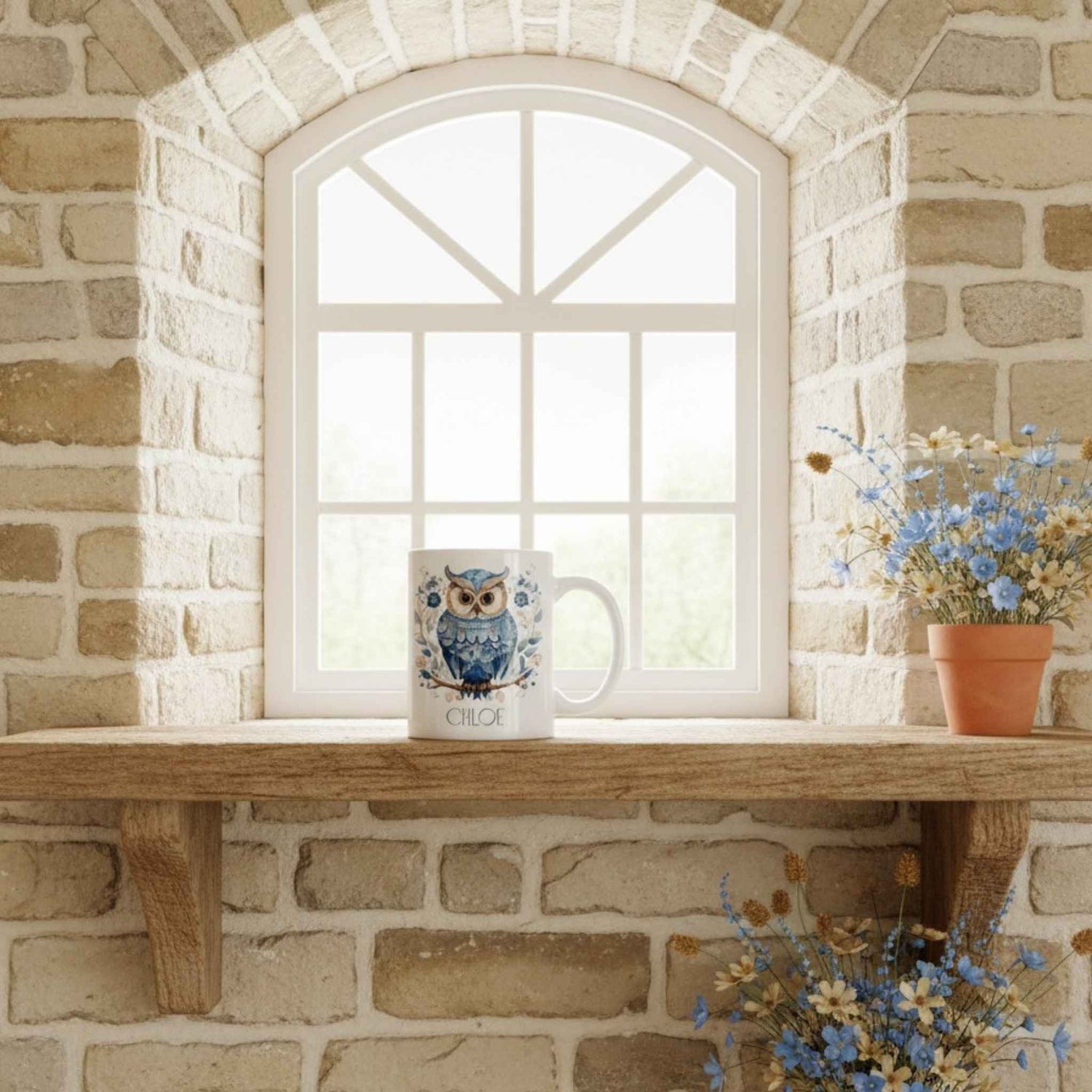 Ceramic mug with owl design on a wooden shelf against a stone wall with a window.