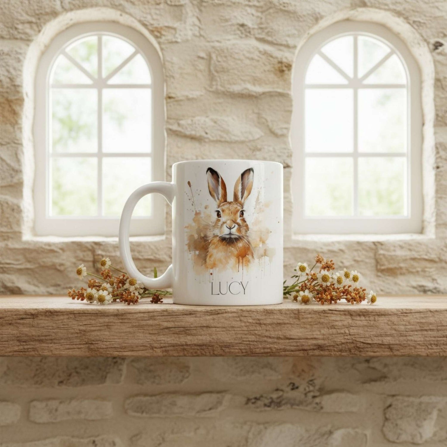 Mug with a hare design and 'Lucy' on a wooden shelf with stone wall and windows in the background