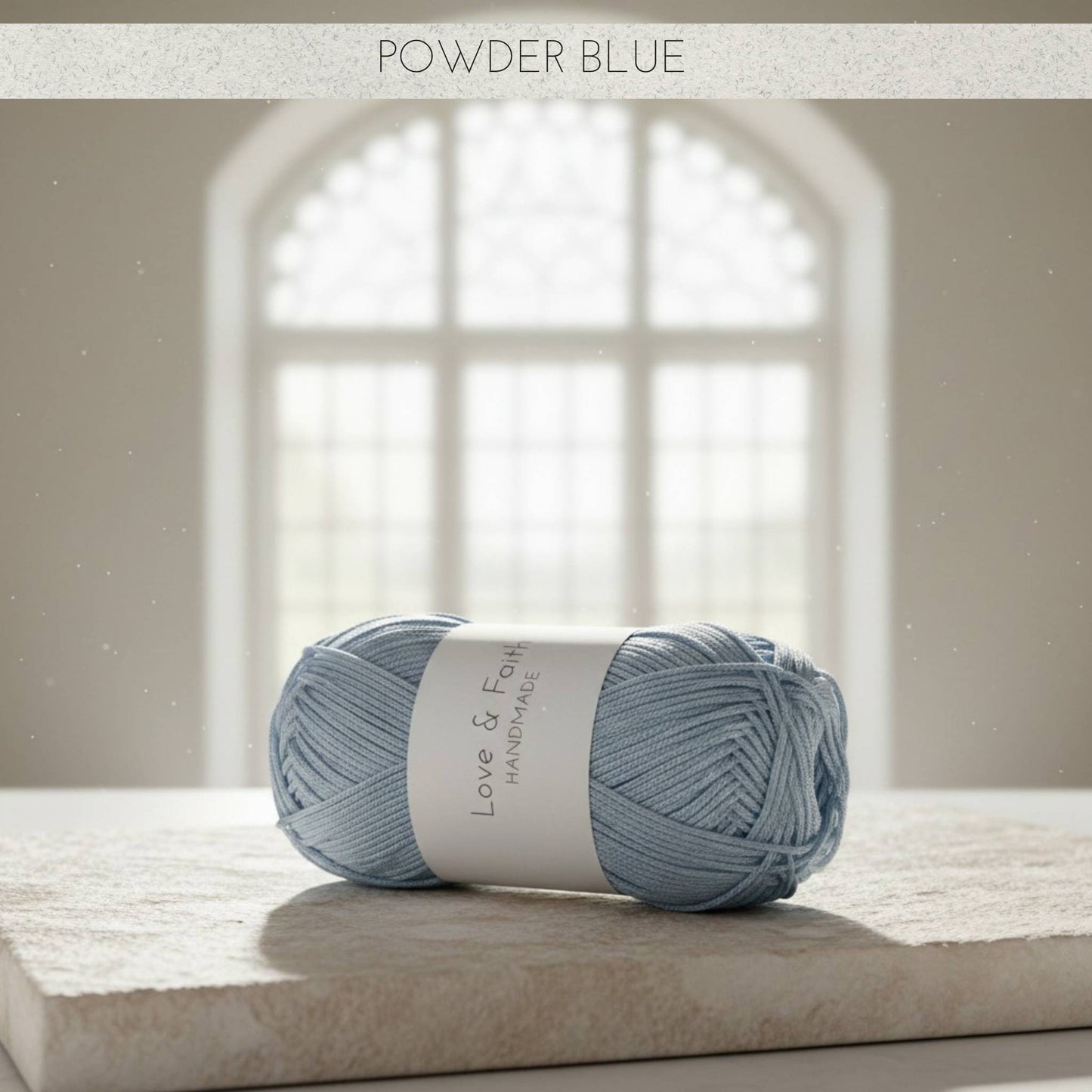 Ball of powder blue yarn on a stone surface with a blurred window background