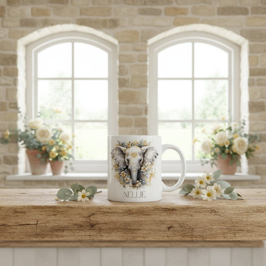 Mug with an elephant design and 'Nellie' text on a wooden surface with flowers and a brick wall background.