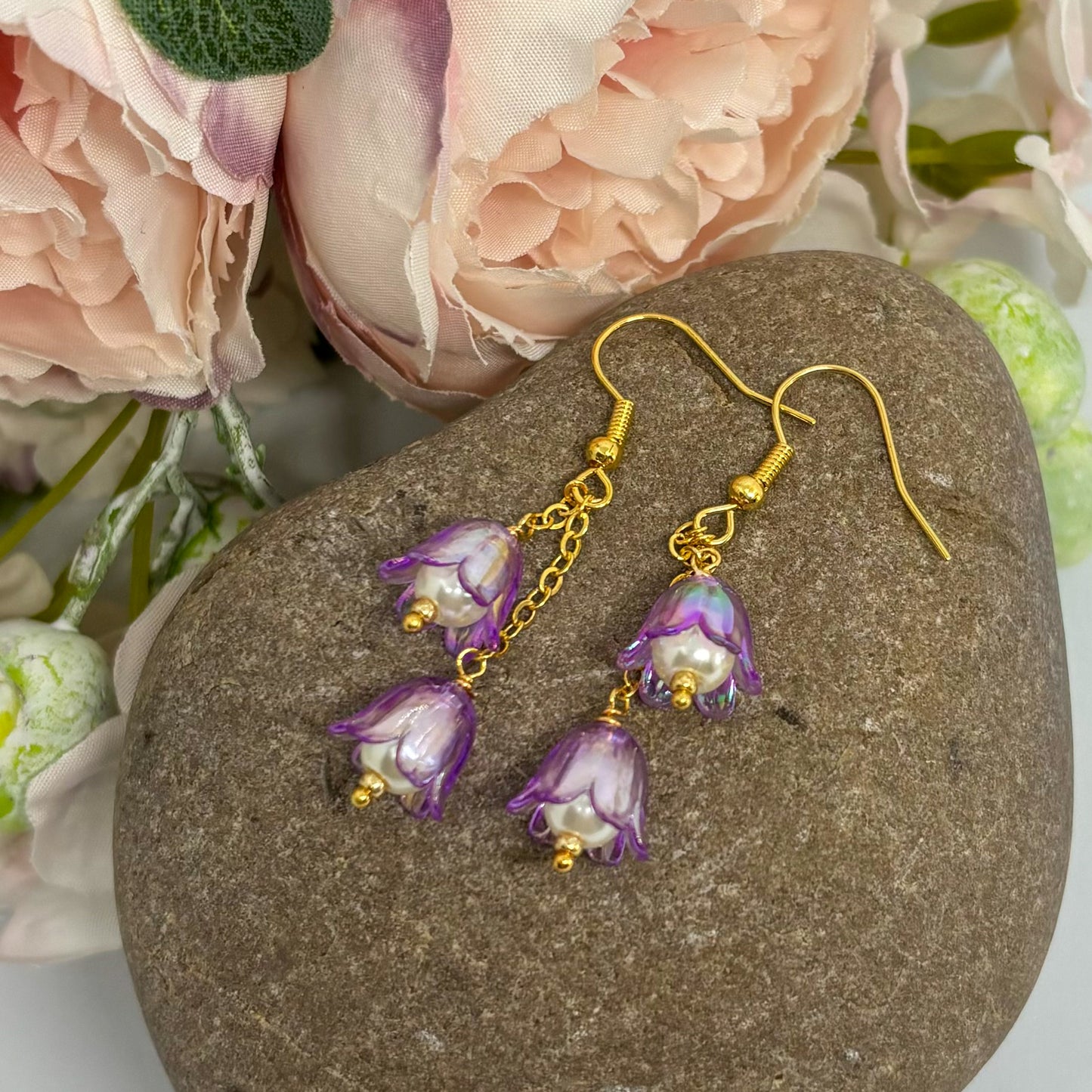 purple tulip floral earrings with gold hooks on a pebble.