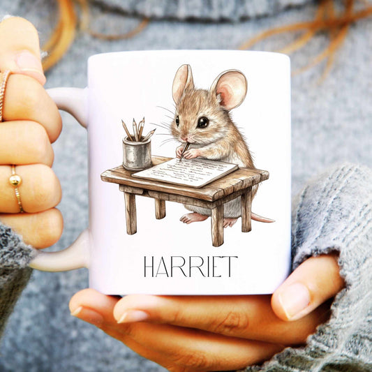 Mug with a mouse illustration and 'Harriet' text held by hands.