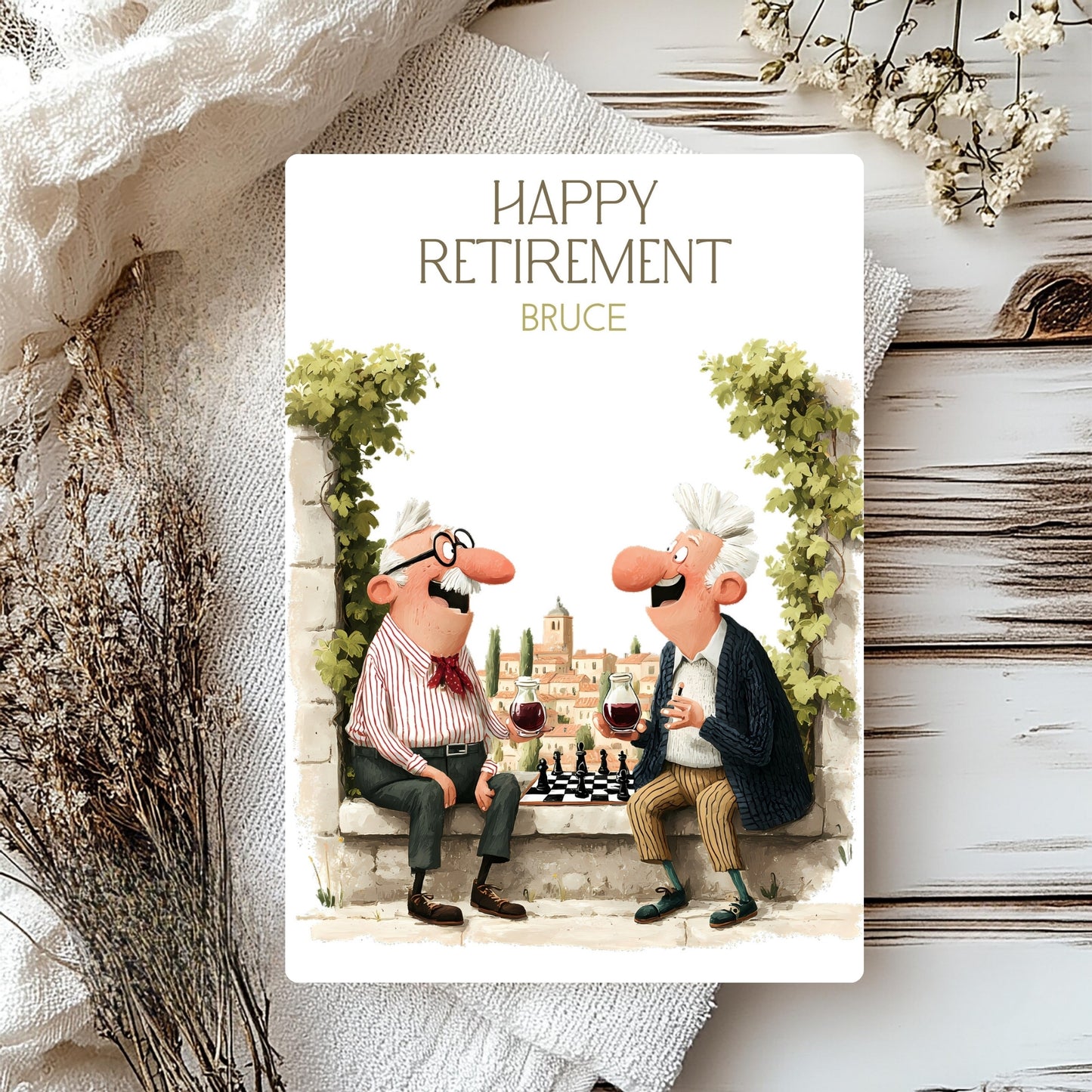 Happy Retirement card with cartoon characters enjoying wine and a game of chess, placed on a textured surface with decorative elements.