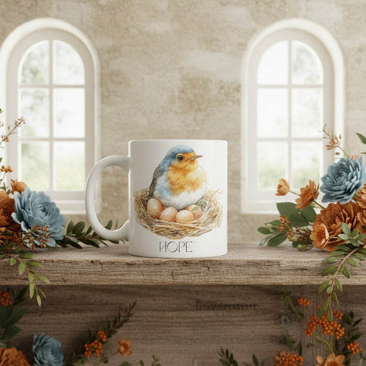 Mug with a robin design and 'HOPE' text on a decorative shelf with flowers.