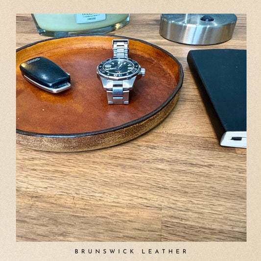 Watch on a leather  tray with a phone and other items, branded 'Brunswick Leather'