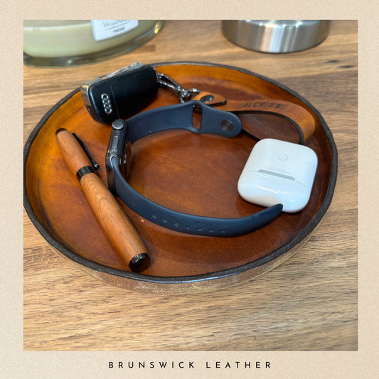 Leather round tray with accessories, branded 'Brunswick Leather'.