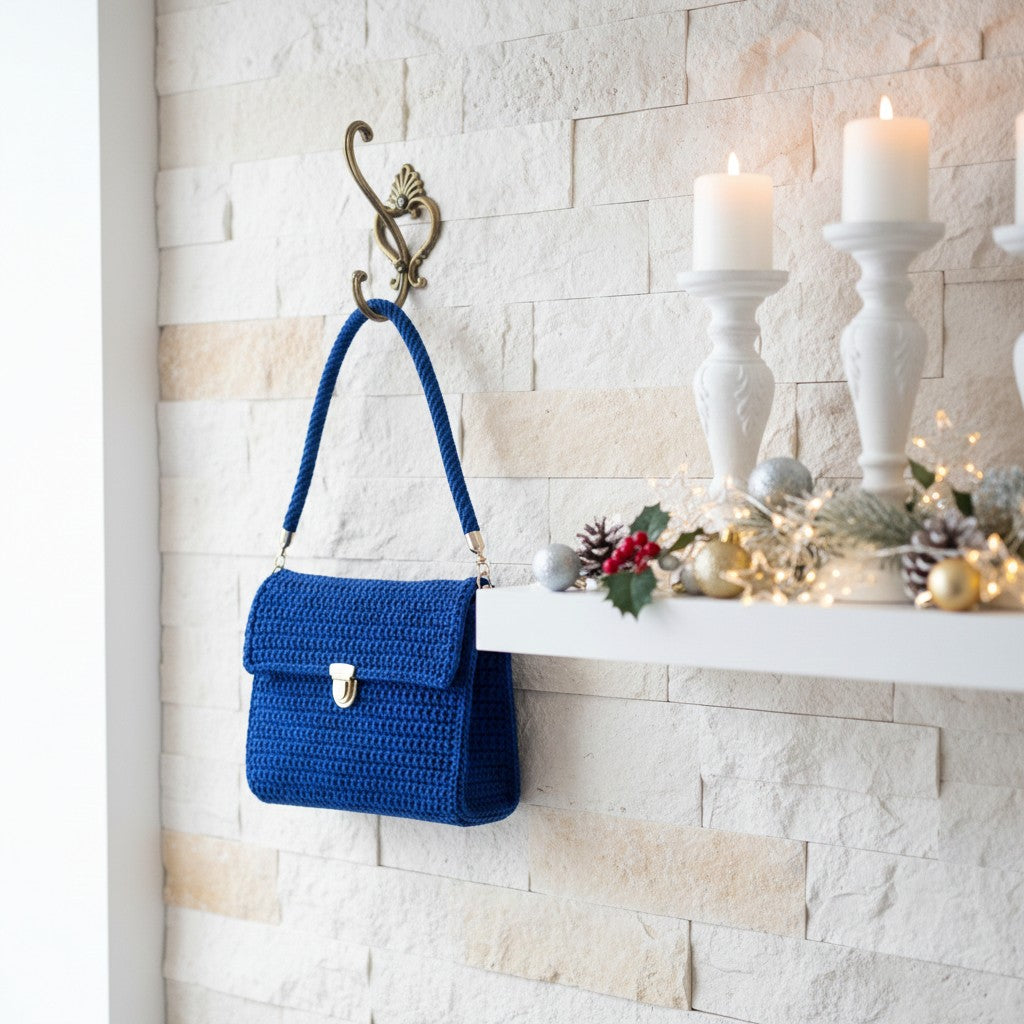 Blue handbag hanging on a hook against a white brick wall with candles and decorations.
