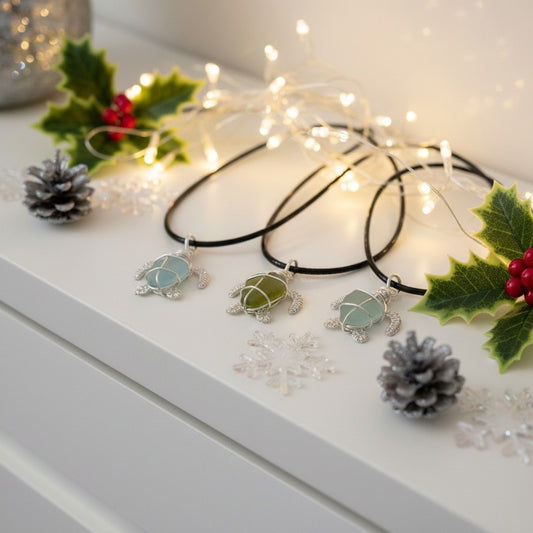 Tortoise-shaped pendants on black cords with Christmas decorative elements on a white surface.
