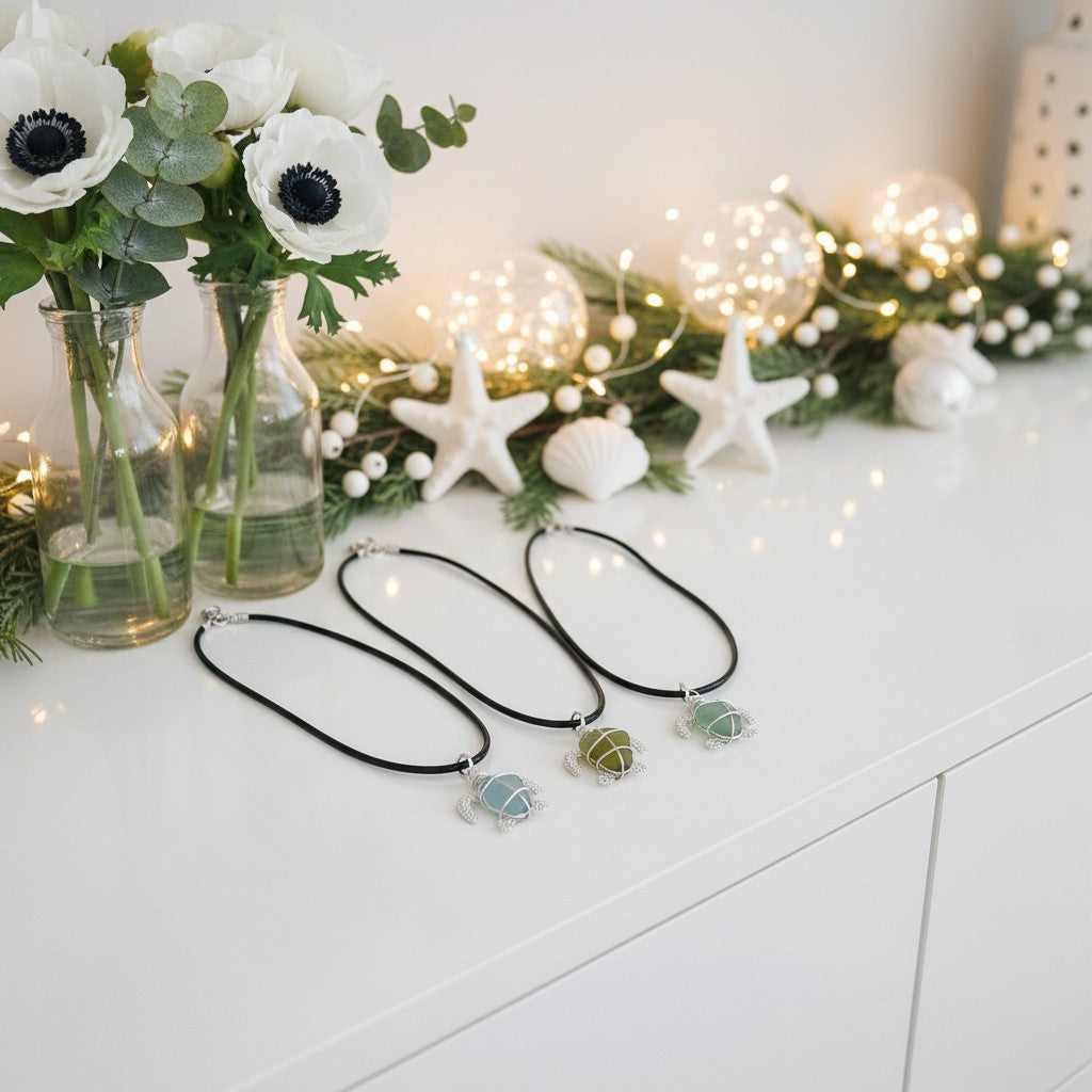 Three necklaces with turtle pendants on a white surface with decorative lights and flowers.