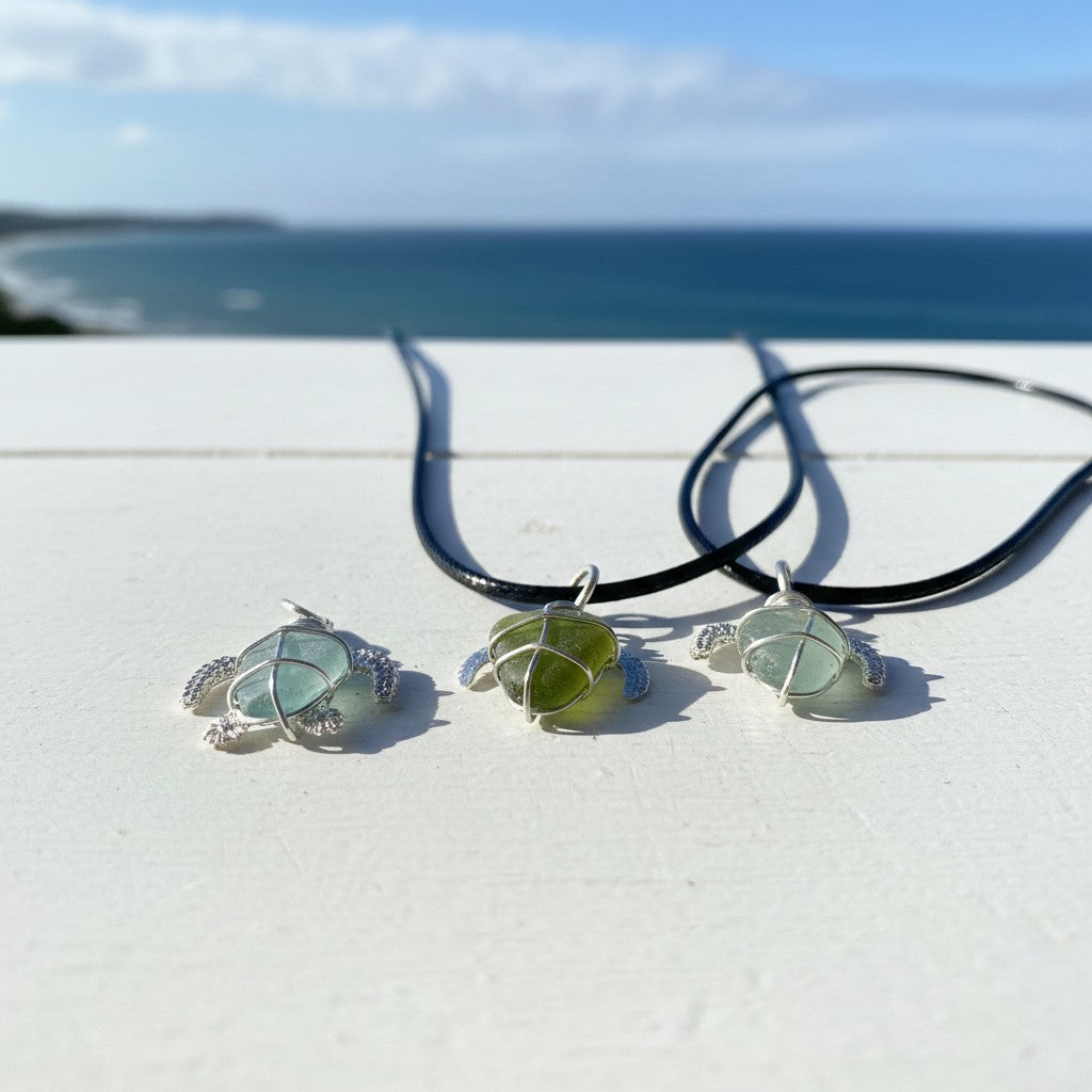 Three green sea glass pendants on black cords with a beach background