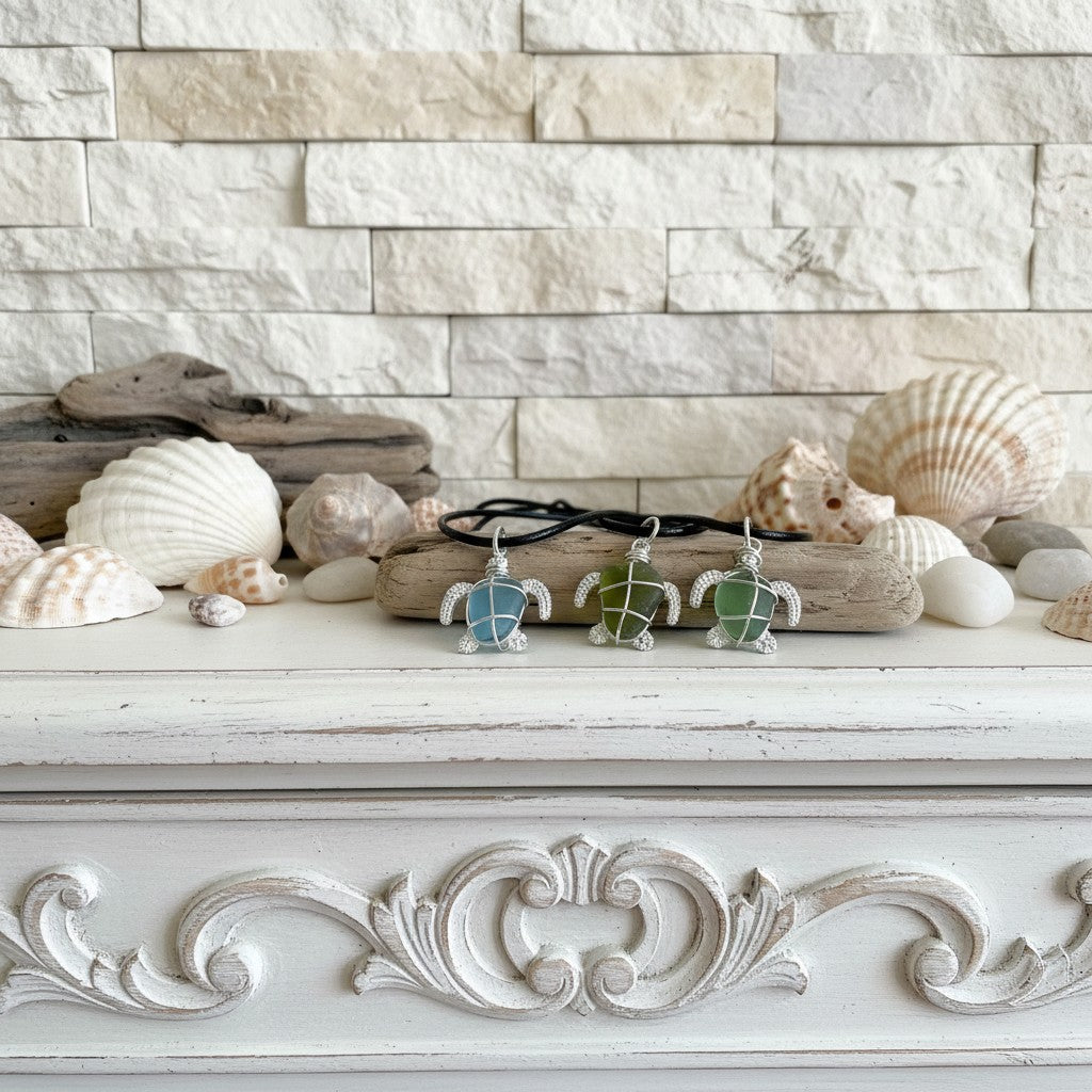 Three sea turtle necklaces on a decorative white surface with shells and driftwood.