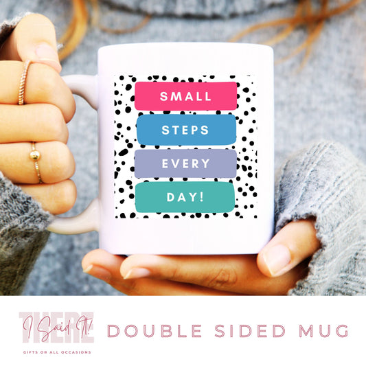 A person holding a white coffee mug with double-sided print. The mug has text on it that says 'SMALL STEPS EVERY DAY' with a spotted print pattern in the background.