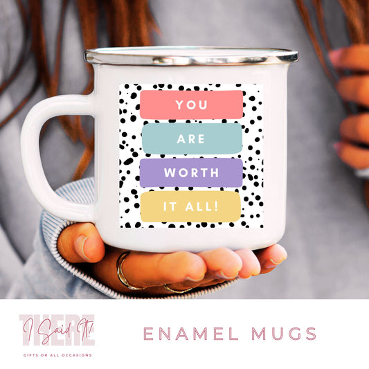 A white ceramic enamel mug with a motivational message 'You are worth it all' printed on it, held in a person's hand.