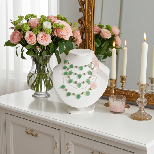 Jewelry display with necklace on a white stand, flowers, and candles on a dresser.