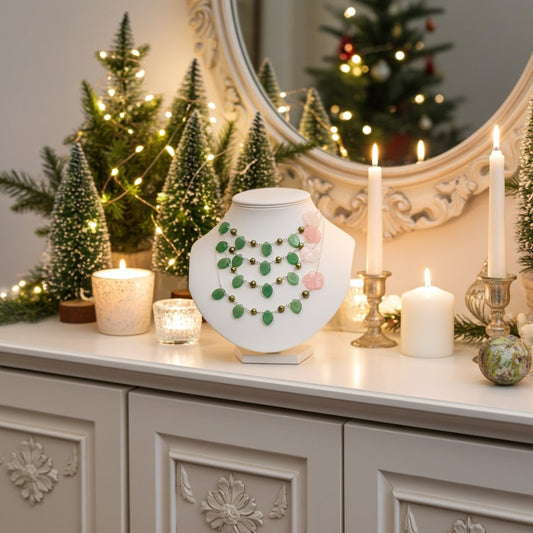 Decorative table setting with a semi precious bead necklaces on a white stand, candles, and Christmas trees in a home interior.