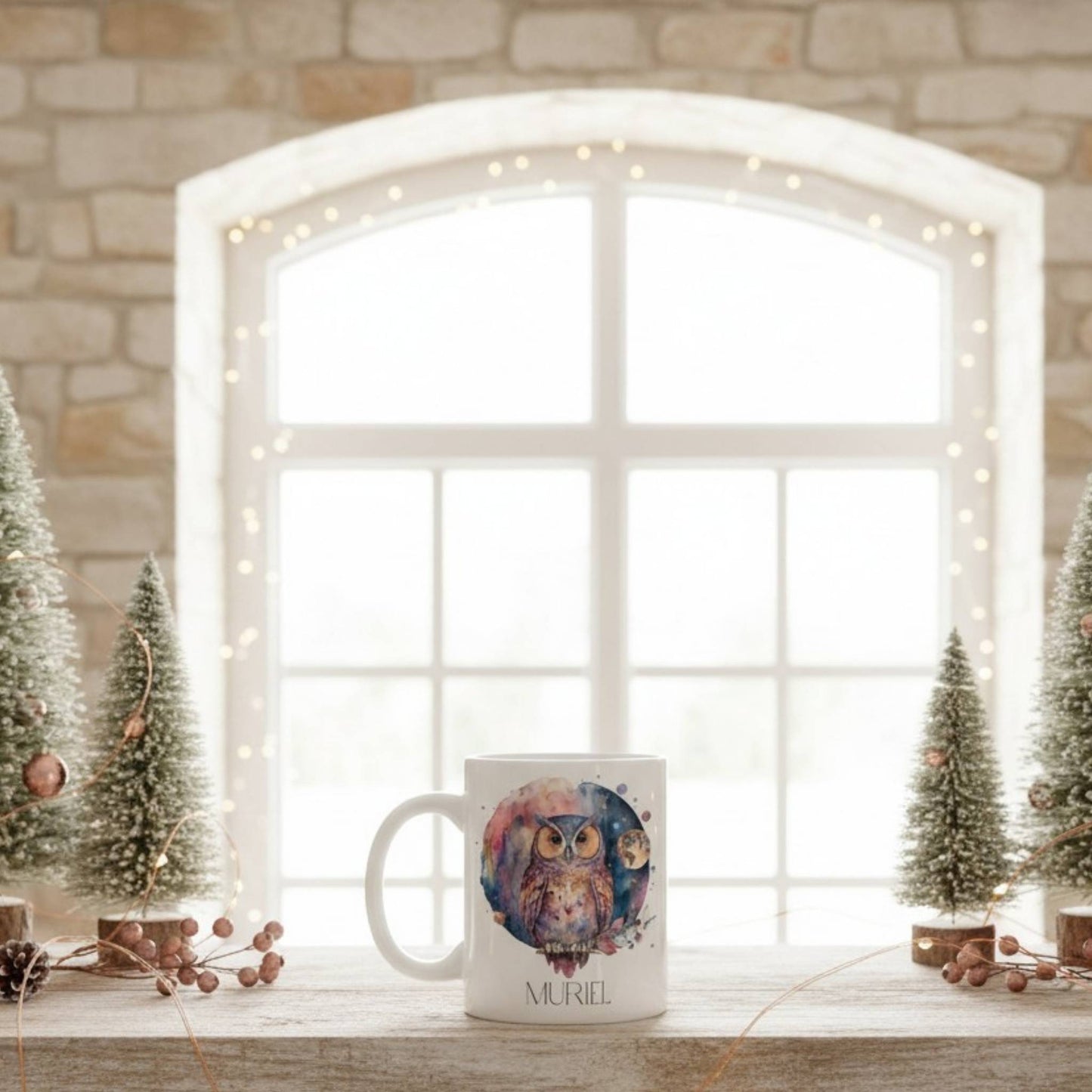 Mug with owl design on a windowsill with decorative trees and lights.