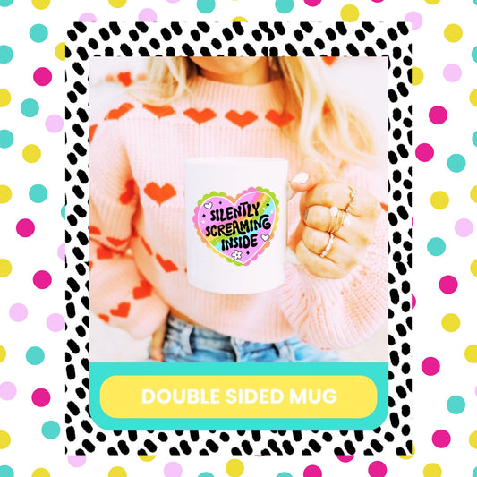A person holding a double-sided mug with a colourful heart and screaming text design on one side, with a polka dot pattern background.