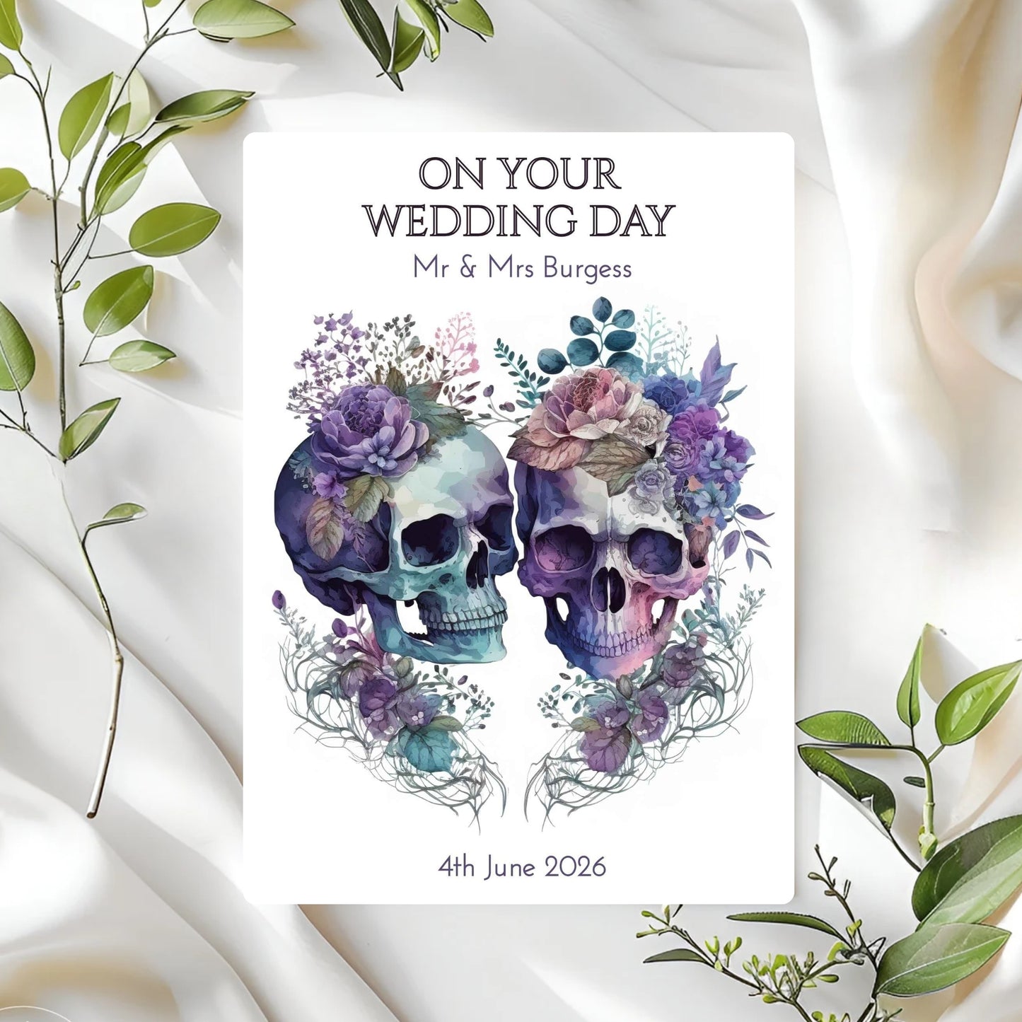 Personalised wedding card with skull and floral design on a white fabric background