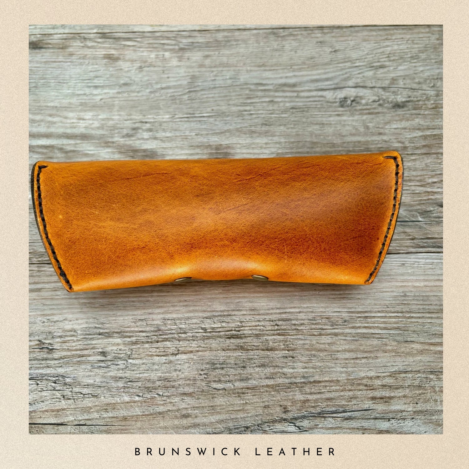 Brown leather case on a wooden surface with 'Brunswick Leather' branding.