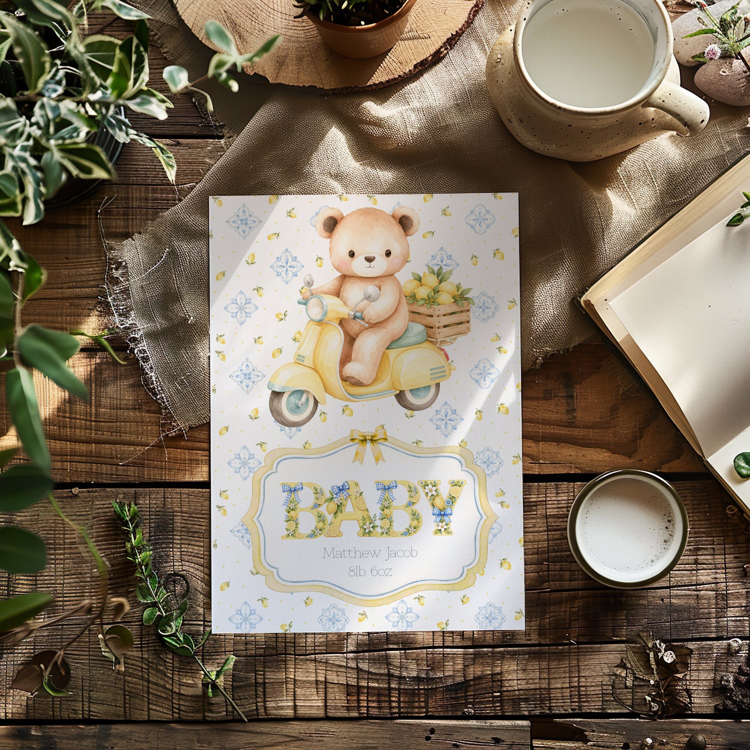 A baby card for a newborn featuring a cute teddy bear on a yellow scooter, styled in a rustic flat-lay with a wooden table, burlap cloth, plants, and coffee cup.