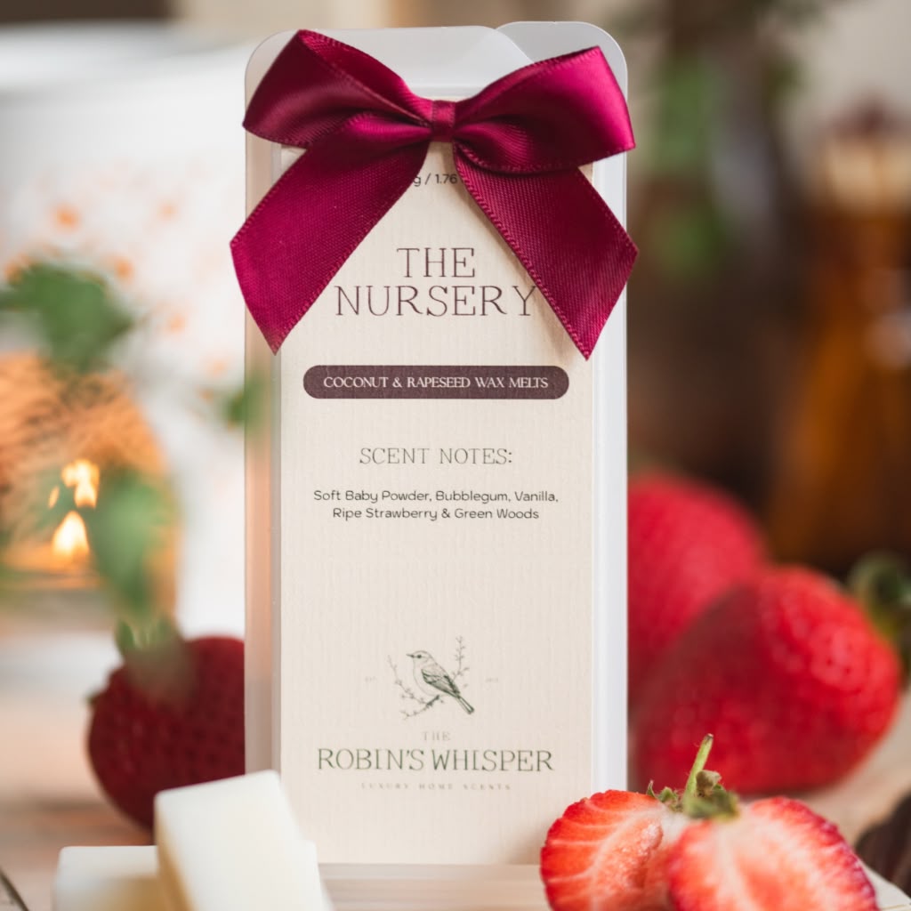 Wax melt packaging with a red bow, surrounded by strawberries, on a blurred background.