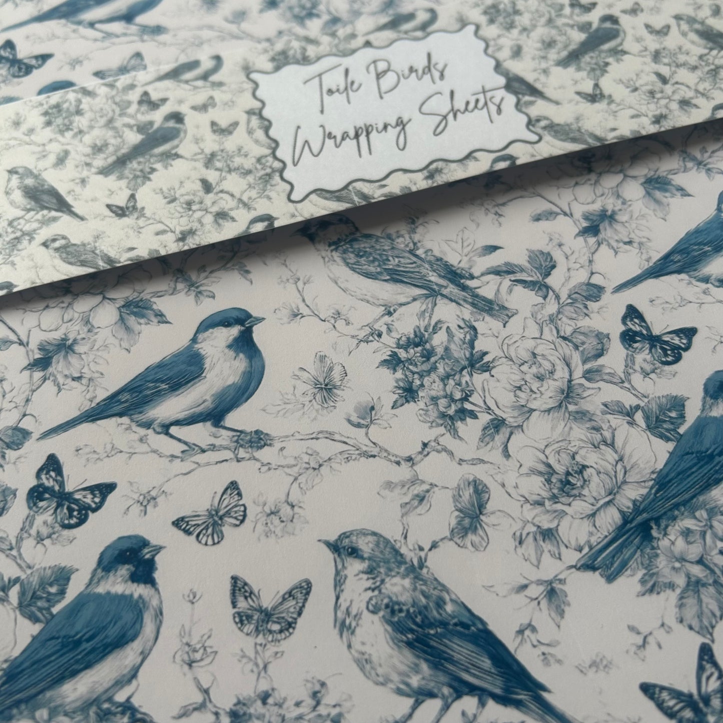Wrapping paper with blue birds and flowers on a white background, featuring the words 'Toile Birds'.