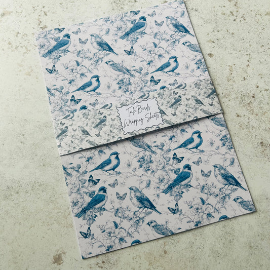 Two sheets of blue bird-patterned paper on a textured surface