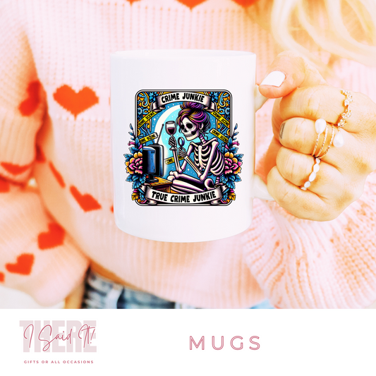 A colourful mug with a design featuring a character and text related to true crime, held by a person with a pink sweater in the background.