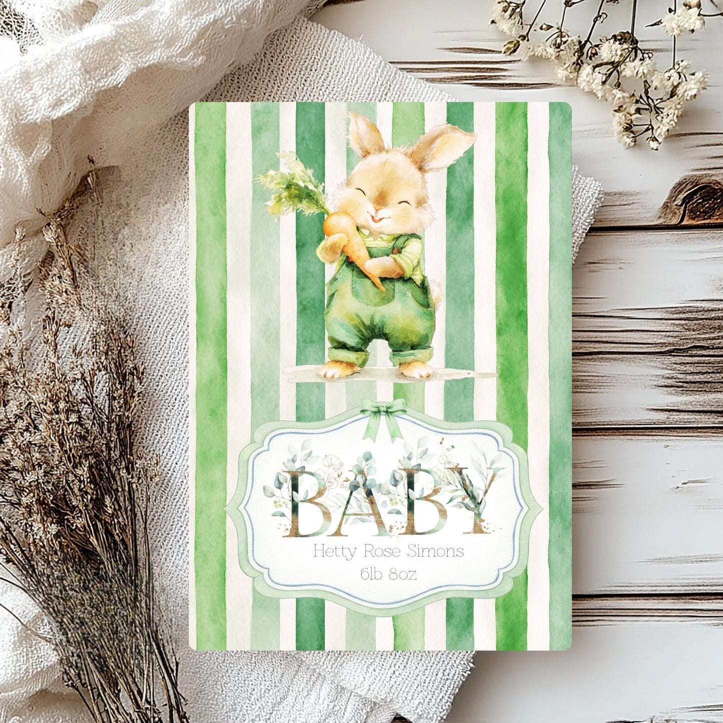 A baby card with a green and white striped cover, featuring a watercolour illustration of a baby rabbit in green clothing and the text 'BABY'