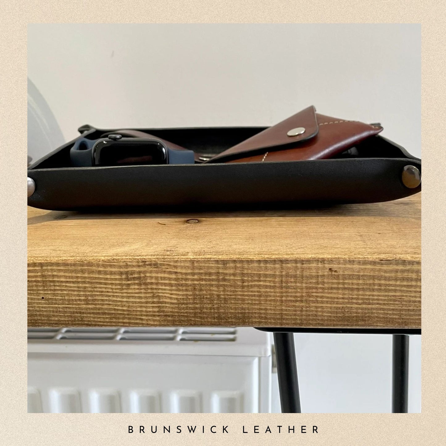 Black leather tray with a brown leather pouch on a wooden surface, branded 'Brunswick Leather'.