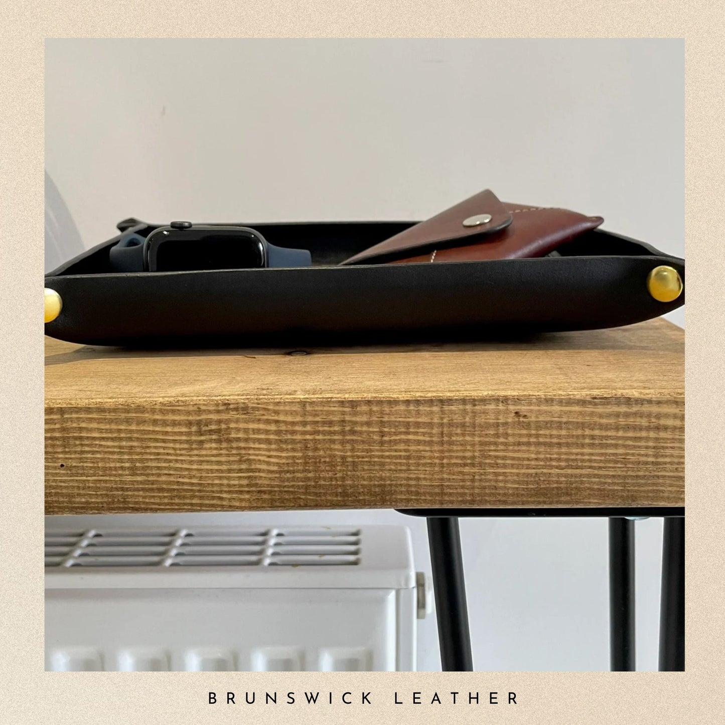 Black tray with a brown leather pouch on a wooden surface, branded 'Brunswick Leather'.