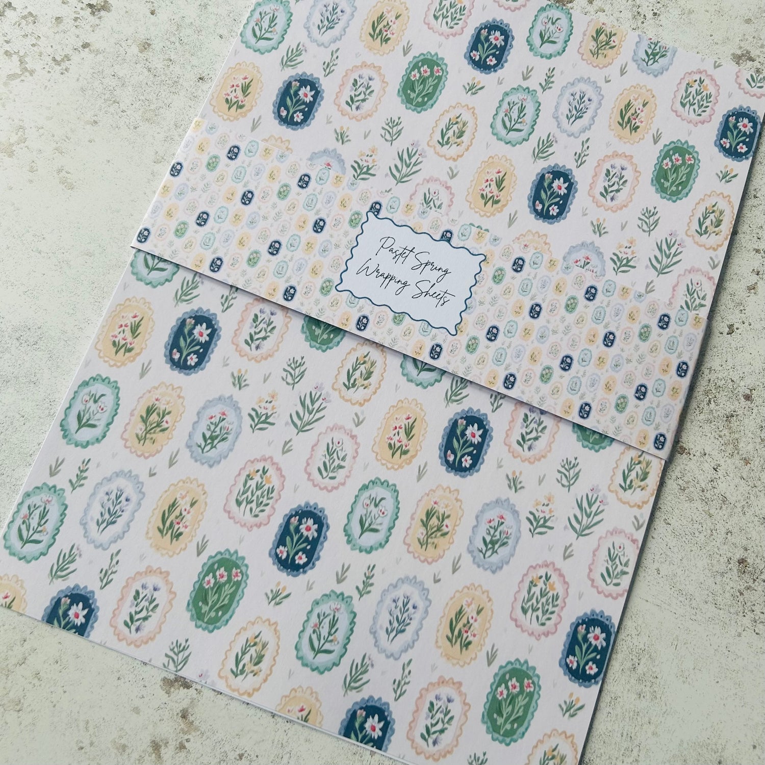 Two sheets of patterned paper with floral designs on a textured surface